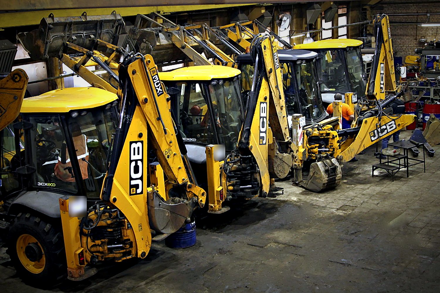 Ряд экскаваторов-погрузчиков JCB на постах ремонта